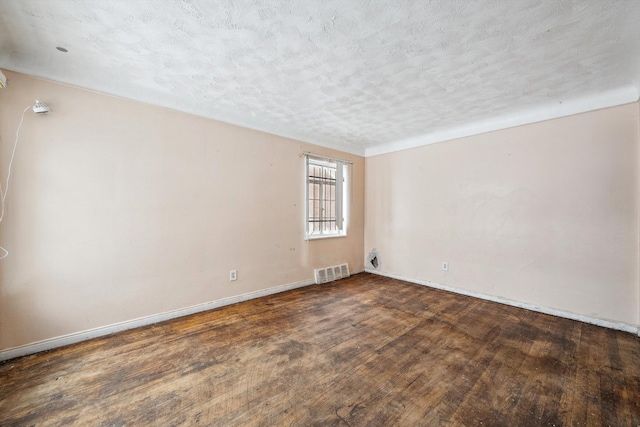 spare room with a textured ceiling and dark hardwood / wood-style floors