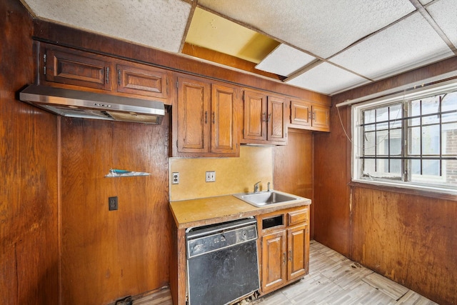 kitchen featuring a paneled ceiling, dishwasher, extractor fan, wooden walls, and sink