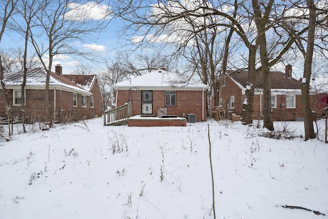 snow covered rear of property with a deck and cooling unit