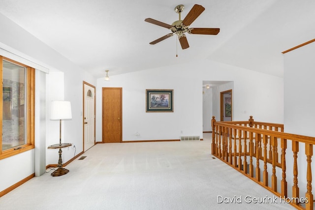 hallway with light carpet, lofted ceiling, and plenty of natural light