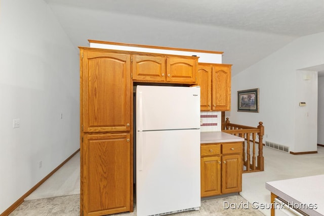 kitchen featuring light colored carpet, lofted ceiling, and white fridge