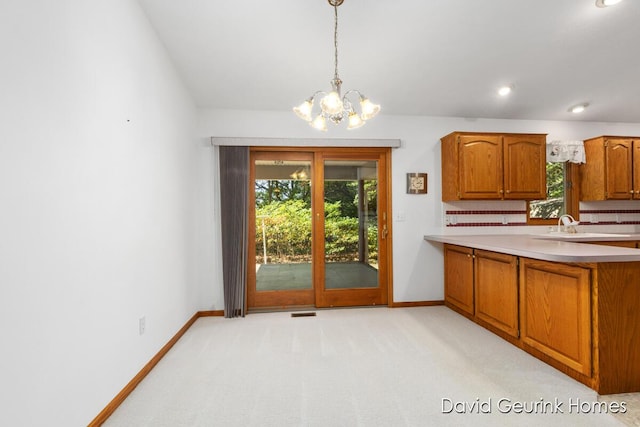 kitchen with decorative light fixtures, light carpet, sink, backsplash, and a chandelier