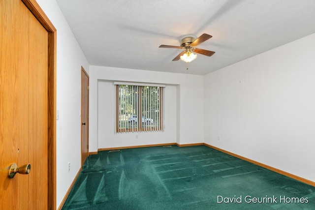 spare room with ceiling fan and dark colored carpet