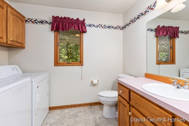 bathroom featuring toilet, vanity, a wealth of natural light, and washing machine and clothes dryer