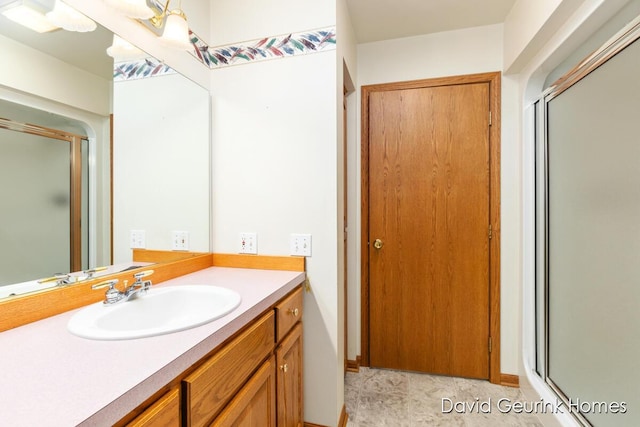 bathroom featuring a shower with shower door and vanity