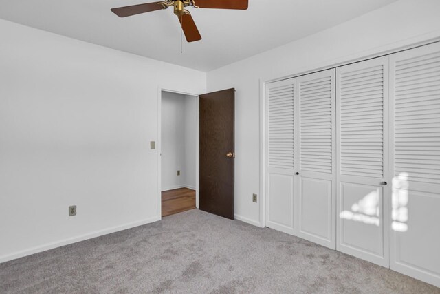 unfurnished bedroom with baseboards, a ceiling fan, a closet, and carpet