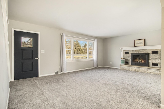 unfurnished living room featuring a stone fireplace and carpet floors