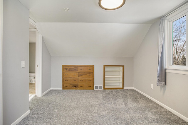 bonus room featuring vaulted ceiling, carpet flooring, and built in shelves