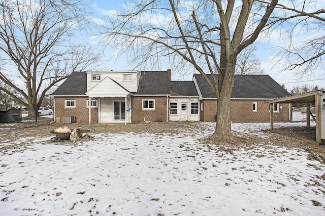 snow covered house featuring cooling unit and an outdoor fire pit