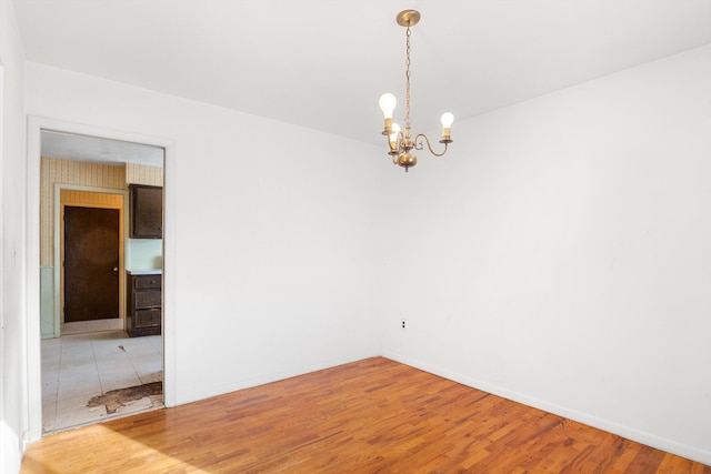 unfurnished room with an inviting chandelier and wood-type flooring