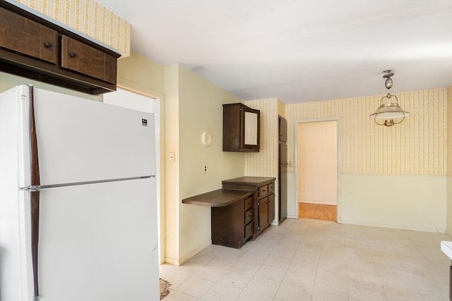 kitchen featuring dark brown cabinets, decorative light fixtures, and white fridge