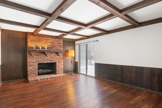 unfurnished living room with wooden walls, coffered ceiling, dark hardwood / wood-style flooring, and beam ceiling