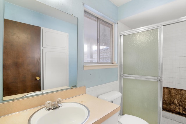 bathroom featuring vanity, toilet, and a shower with shower door