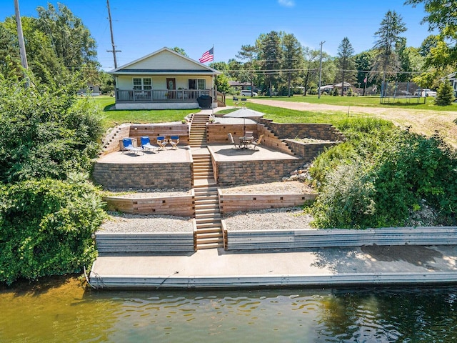 back of property featuring a patio, a water view, and a yard