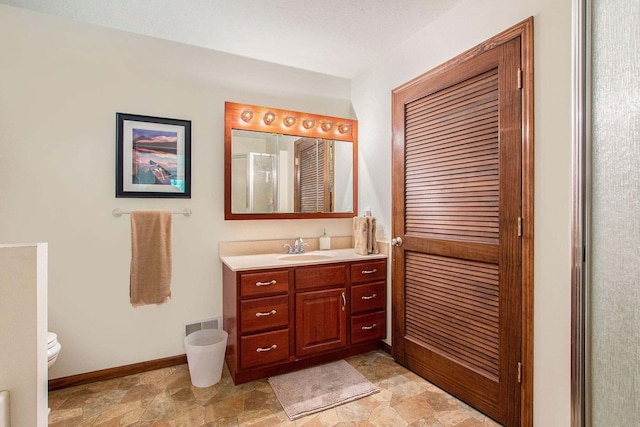 bathroom featuring vanity, toilet, and a shower with shower door