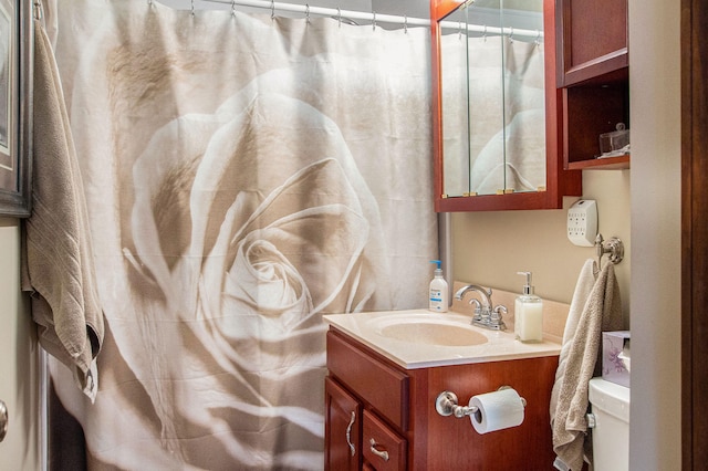 bathroom with curtained shower, toilet, and vanity