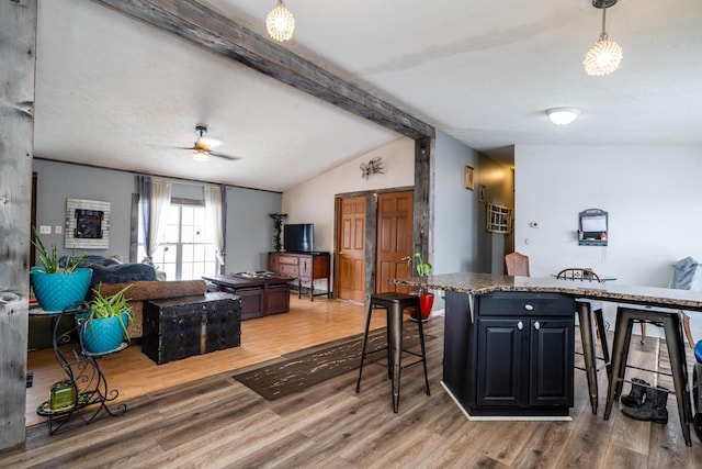 kitchen with lofted ceiling with beams, wood-type flooring, a kitchen breakfast bar, and decorative light fixtures