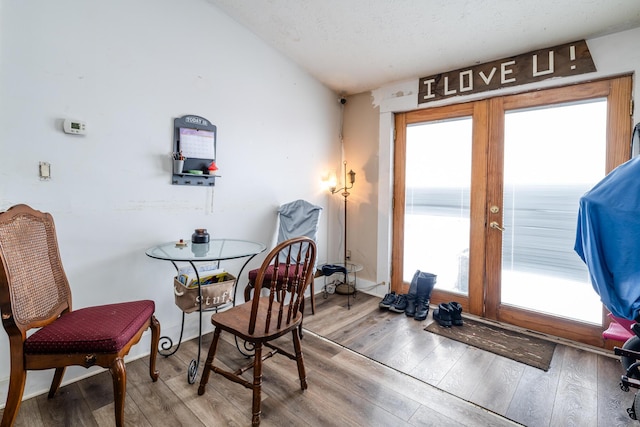 living area with hardwood / wood-style flooring, a textured ceiling, and lofted ceiling