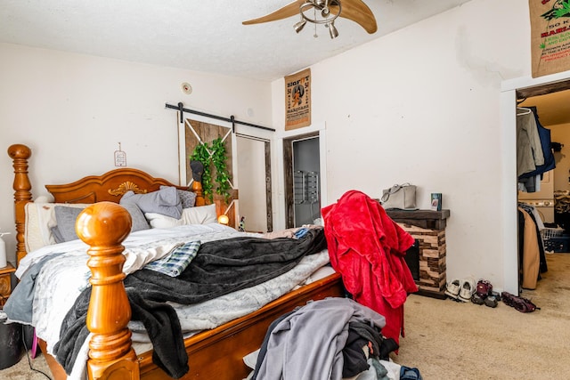 carpeted bedroom with ceiling fan and a barn door