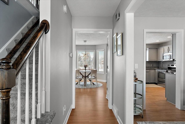 corridor featuring a textured ceiling and light wood-type flooring