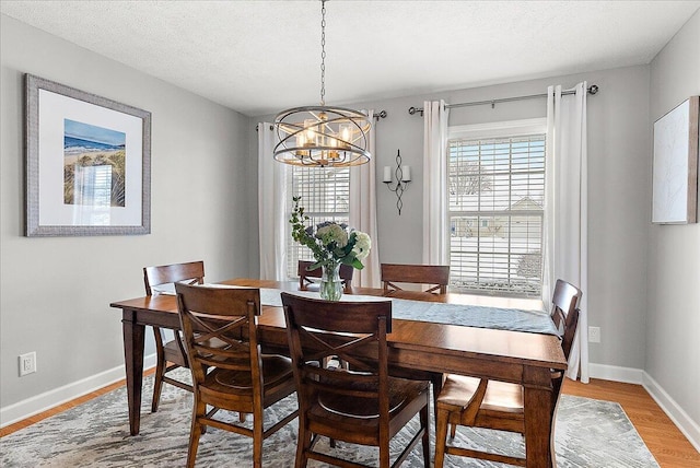 dining space featuring light hardwood / wood-style floors, a textured ceiling, and a notable chandelier