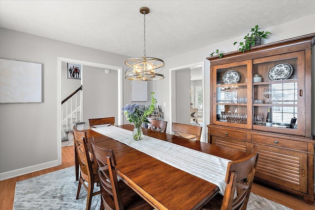 dining area with a textured ceiling, a chandelier, and hardwood / wood-style flooring