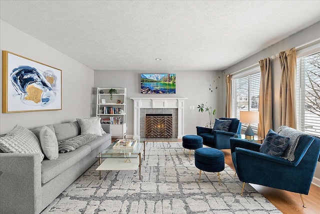 living room featuring a tiled fireplace, a textured ceiling, and hardwood / wood-style flooring