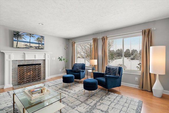 living room with a textured ceiling, a tile fireplace, and light wood-type flooring