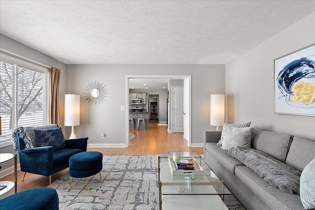 living room with a textured ceiling, a wealth of natural light, and light wood-type flooring