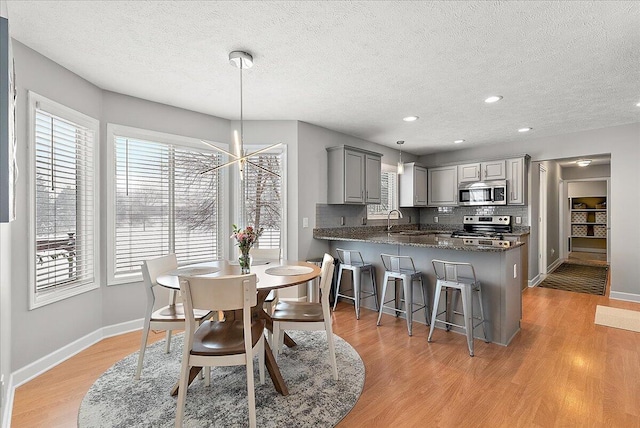 dining area with a textured ceiling, light hardwood / wood-style flooring, and sink