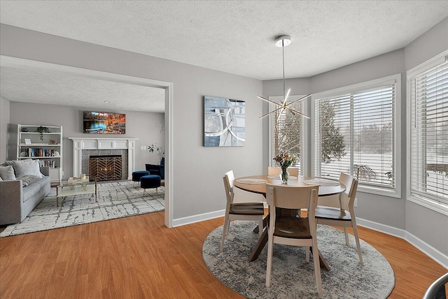 dining room featuring hardwood / wood-style floors, a textured ceiling, a notable chandelier, and a fireplace