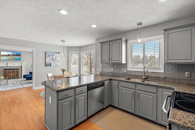 kitchen with kitchen peninsula, gray cabinets, decorative light fixtures, dishwasher, and sink