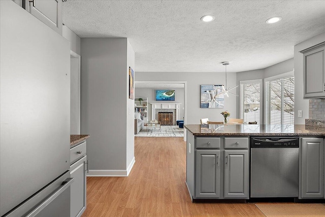 kitchen featuring light hardwood / wood-style floors, gray cabinets, stainless steel appliances, dark stone countertops, and pendant lighting