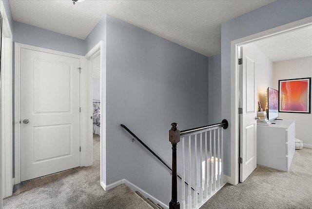 stairway with a textured ceiling and carpet floors