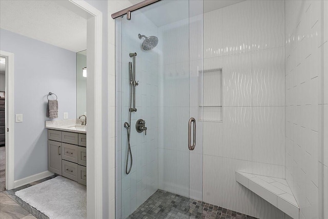 bathroom with a shower with shower door, vanity, and a textured ceiling