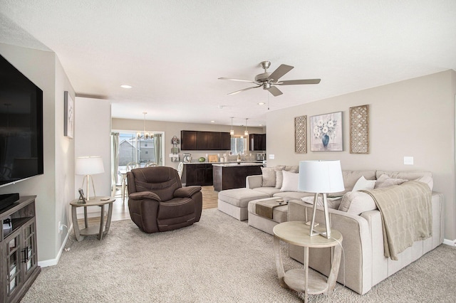 carpeted living room with ceiling fan with notable chandelier