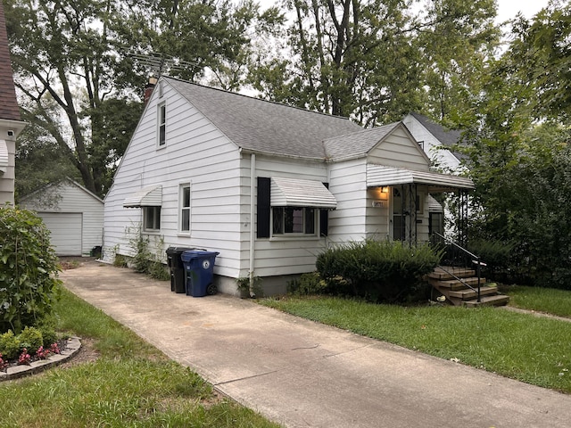 view of front of property featuring a front lawn, a garage, and an outbuilding