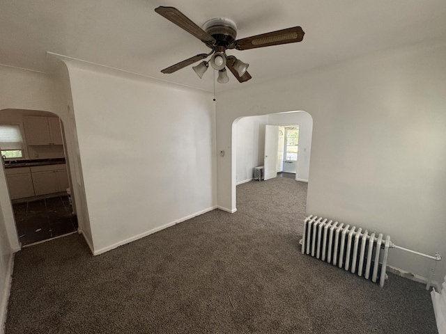 carpeted empty room featuring ceiling fan and radiator heating unit