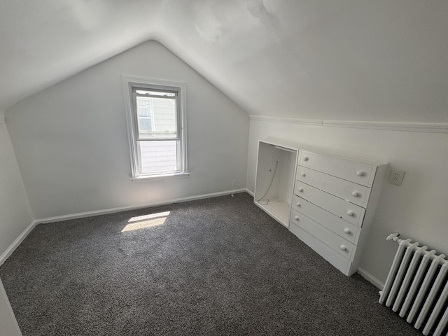 additional living space featuring dark carpet, radiator heating unit, and vaulted ceiling