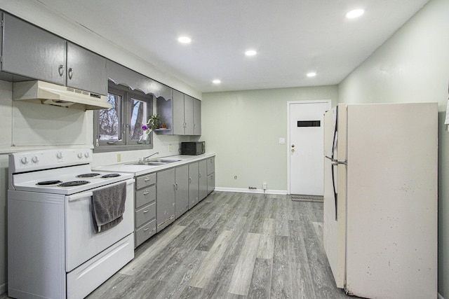 kitchen with light wood-type flooring, sink, and white appliances