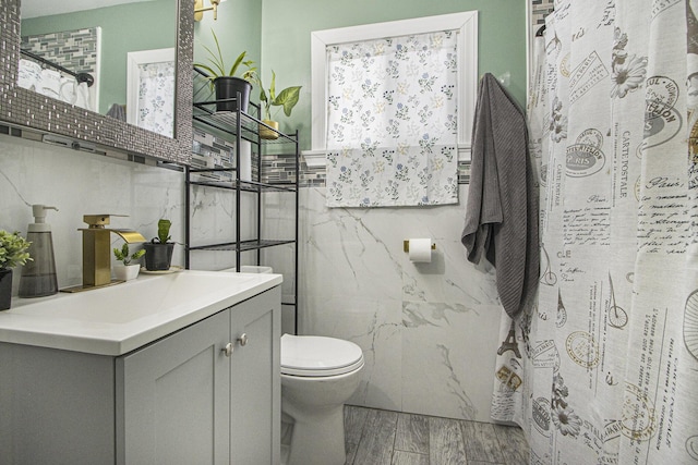 bathroom with toilet, vanity, tile walls, and curtained shower