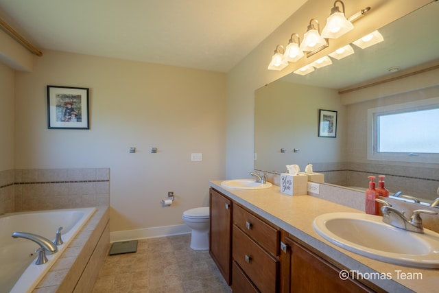 bathroom featuring toilet, tiled tub, and vanity