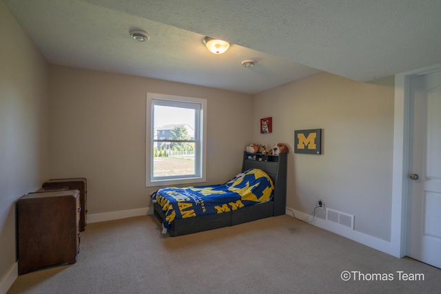 bedroom featuring light carpet and a textured ceiling