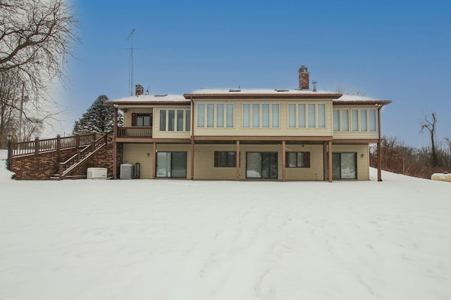 snow covered rear of property with central AC unit