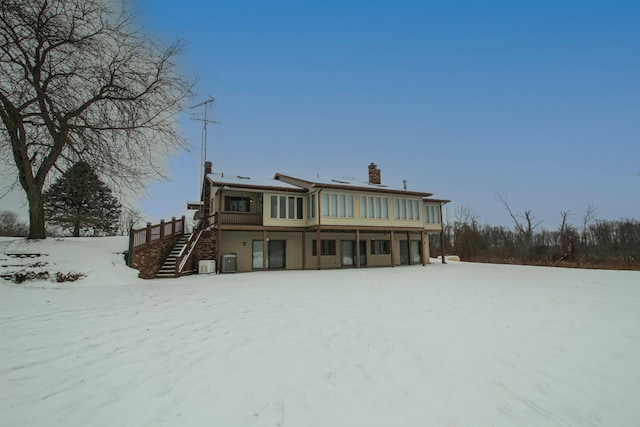 snow covered back of property featuring cooling unit