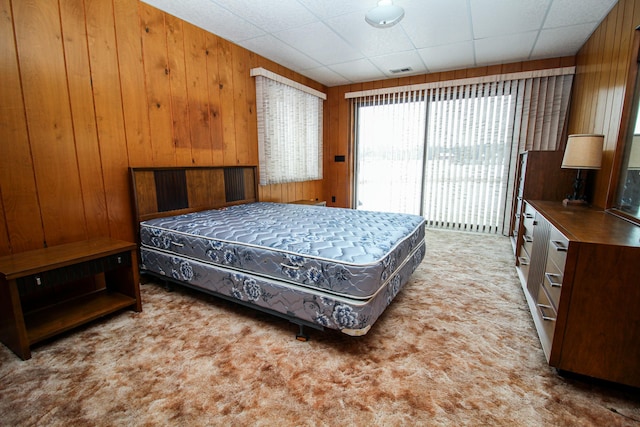 carpeted bedroom with wood walls and access to exterior