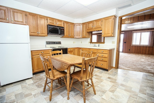 kitchen with electric range oven, white fridge, light carpet, and a drop ceiling