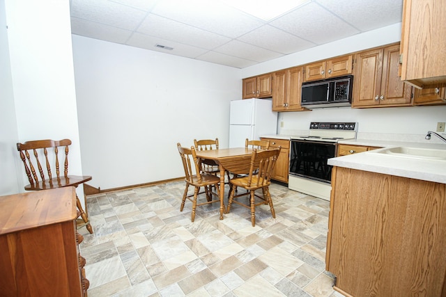 kitchen with sink, white appliances, and a paneled ceiling