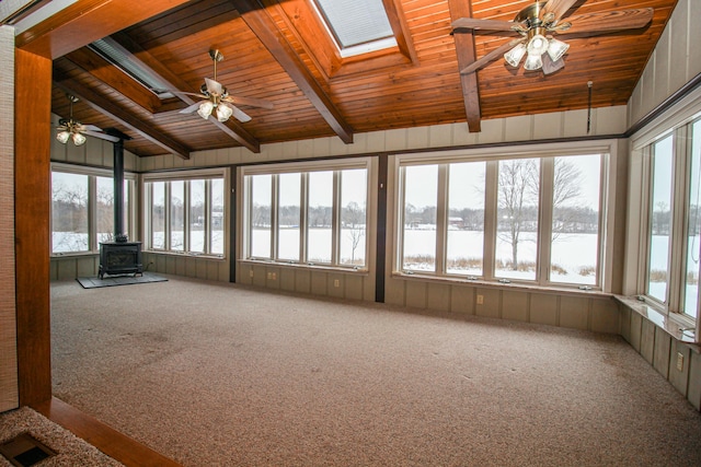 unfurnished sunroom featuring ceiling fan, lofted ceiling with skylight, a water view, a wood stove, and wood ceiling