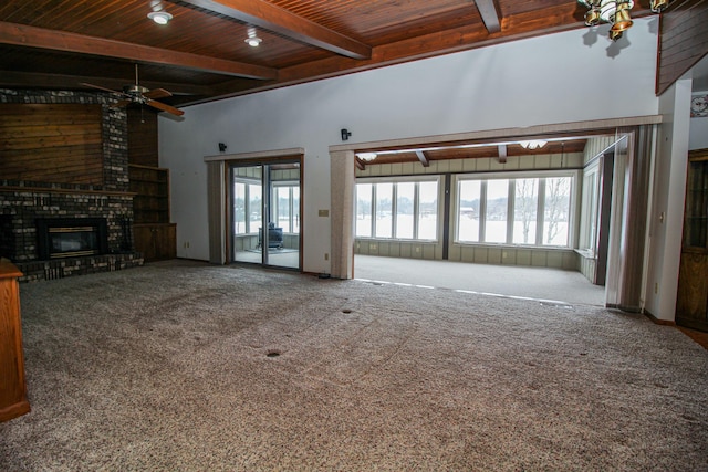 unfurnished living room with carpet, wood ceiling, beamed ceiling, ceiling fan, and a brick fireplace